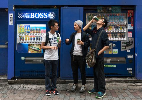 Jeunes hommes à l'aide d'un distributeur automatique de boissons, région de Kanto, Tokyo, Japon ...
