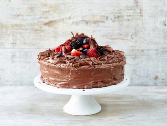 chocolate cake with berries on top and on a cake stand with chocolate shavings