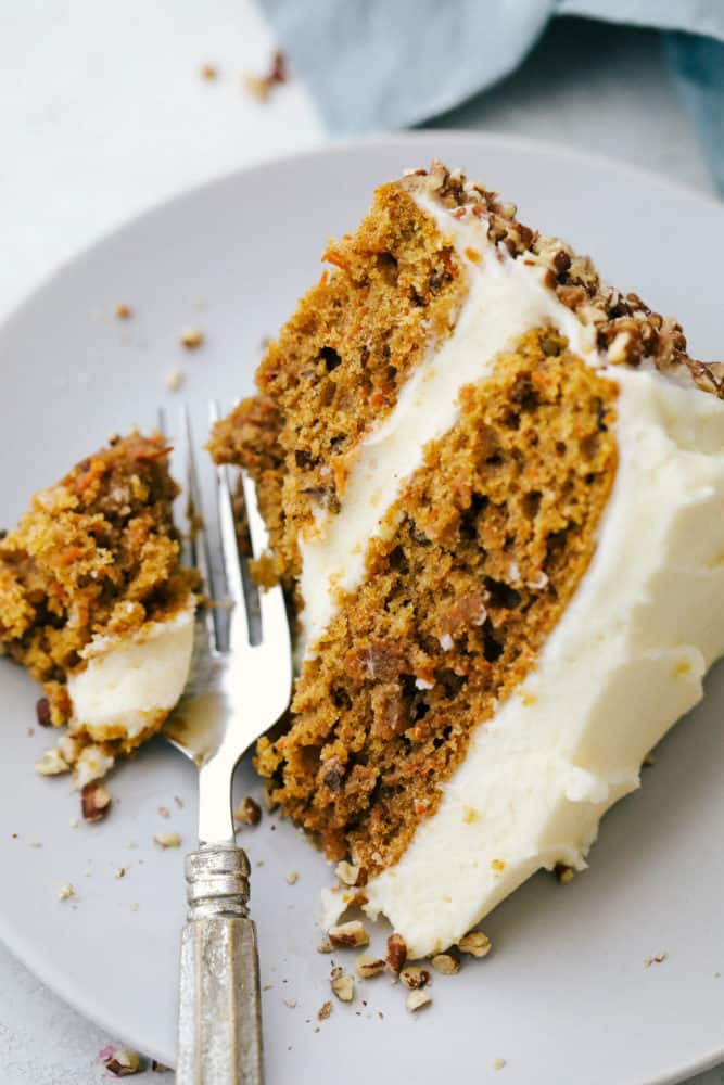 Gâteau aux carottes sur une assiette avec une fourchette coupant une bouchée. 
