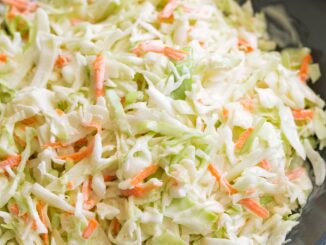 Coleslaw in a blue serving bowl set over a grey surface.