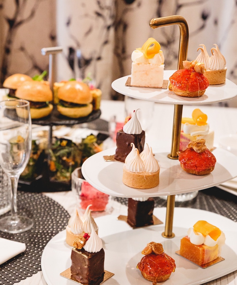 une table avec une haute tour de thé remplie de friandises