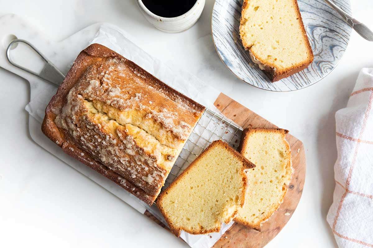 Gâteau quatre-quarts sans gluten cuit dans un moule à pain et coupé en tranches sur une planche à découper en bois