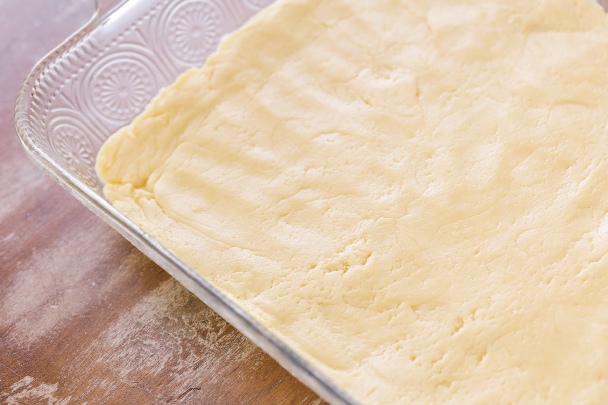 Le gâteau au beurre gluant est un dessert simple et incroyablement délicieux avec une croûte de pâte à gâteau et un dessus de fromage à la crème doux et gluant qui le rend addictif! Croûte de gâteau au beurre gluant Ooey dans un plat de cuisson en verre