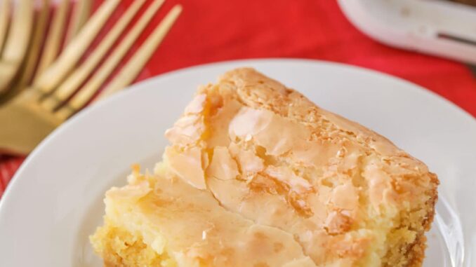 A slice of ooey gooey butter cake on a white plate