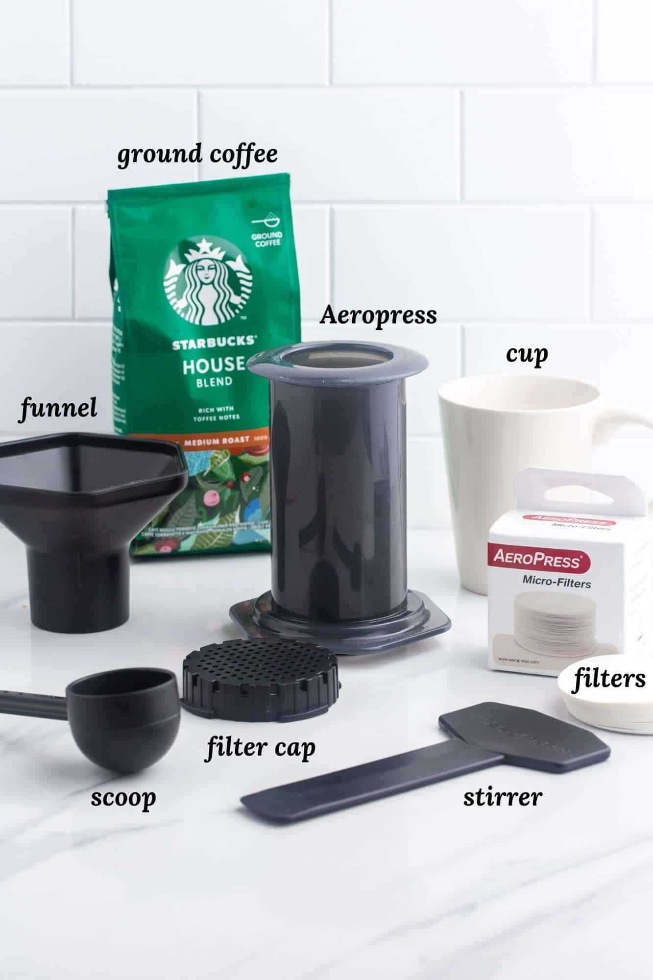 ce dont vous avez besoin pour faire du café aeropress, y compris l'infuseur, les pièces et les accessoires, un sac de café Starbucks et une tasse à café