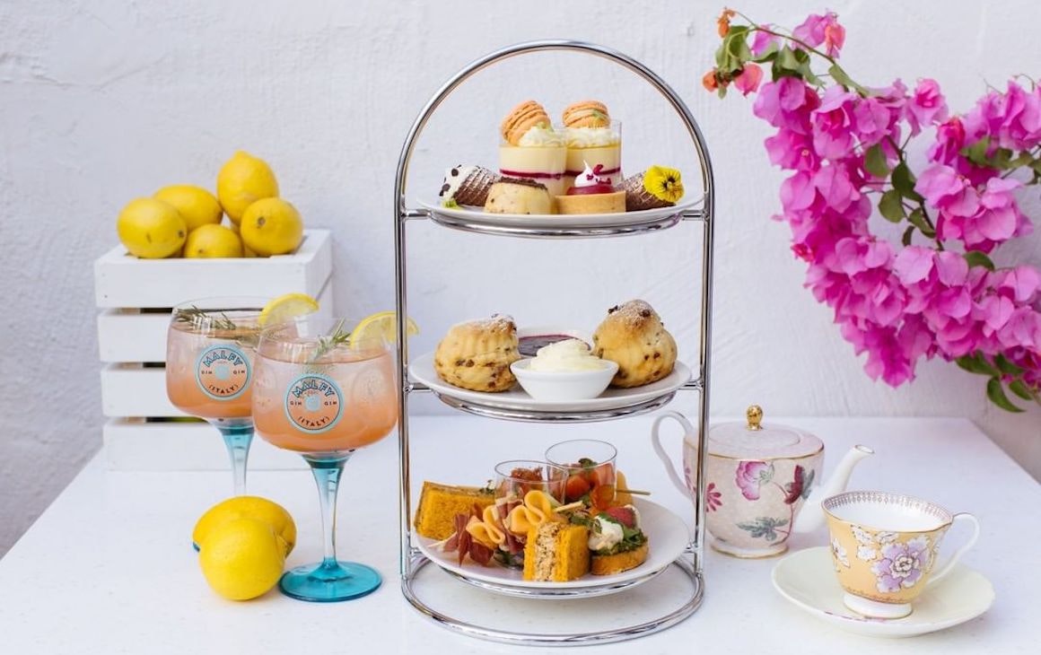 une haute tour de thé remplie de friandises à côté de cocktails