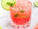 pink drink in short glass with mint inside garnished with a lime wheel and sprig of mint
