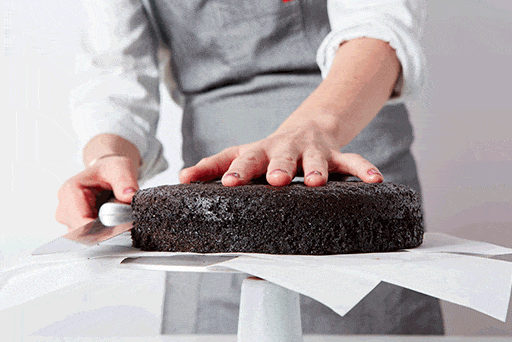 Un boulanger utilisant un couteau dentelé pour diviser un gâteau en deux couches minces.
