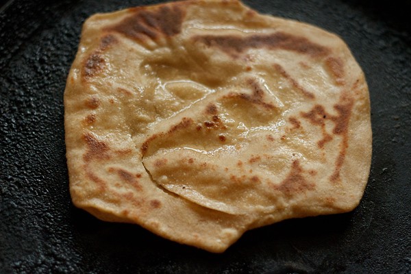 retourner et rôtir le paratha sur tawa